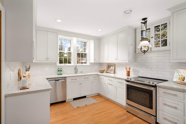 5352 15th Ave S, Minneapolis, MN 55417 - kitchen with stainless steel appliances, tasteful backsplash, light wood-style floors, white cabinetry, and light stone countertops