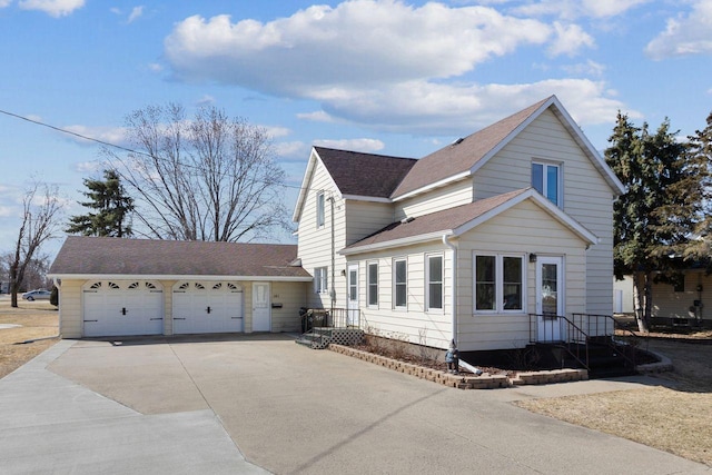 traditional-style home featuring a shingled roof, a garage, and concrete driveway