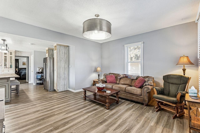living area featuring light wood finished floors, baseboards, and a textured ceiling