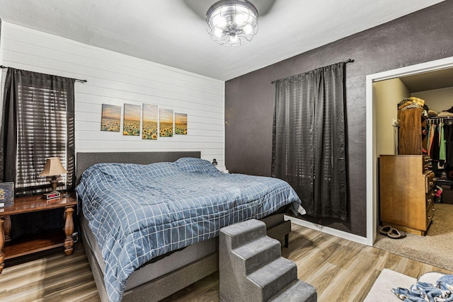 bedroom featuring a walk in closet, a closet, and wood finished floors