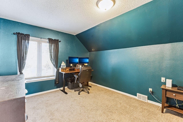 home office featuring a textured ceiling, carpet floors, lofted ceiling, and visible vents
