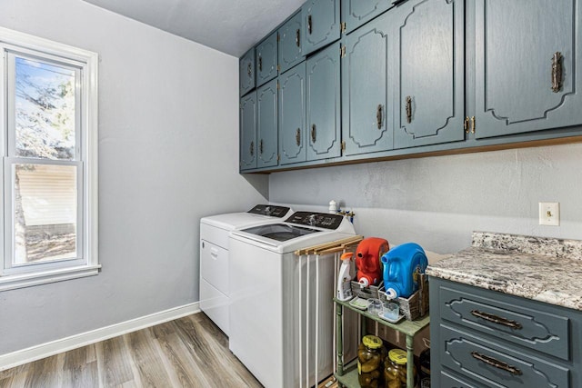 clothes washing area featuring baseboards, cabinet space, washing machine and dryer, and wood finished floors