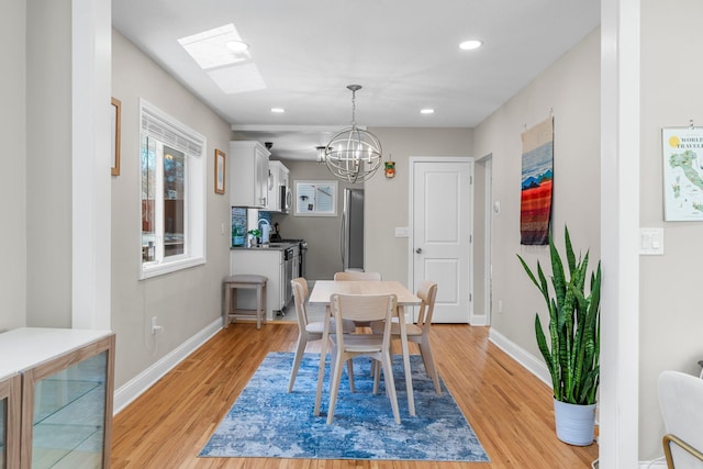 1332 Jersey Ave S, Saint Louis Park, MN 55426 - dining area featuring a skylight, light wood-style floors, baseboards, a notable chandelier, and recessed lighting