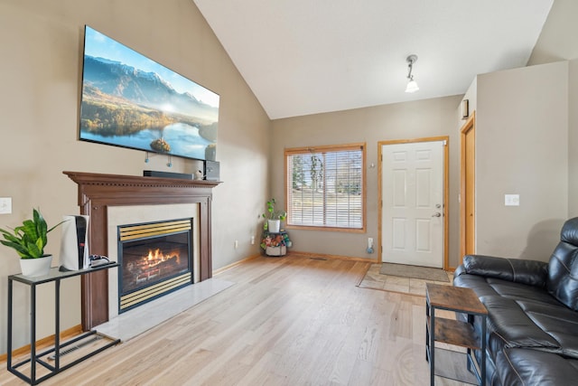 living room with baseboards, lofted ceiling, a fireplace, and wood finished floors
