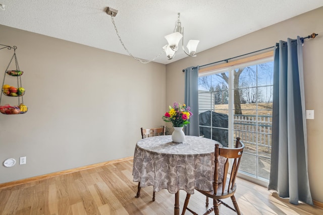 dining room with a notable chandelier, baseboards, light wood-style floors, and a textured ceiling