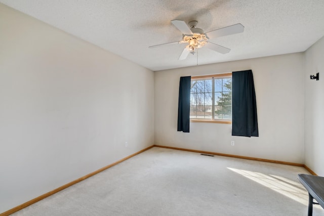 spare room featuring carpet flooring, a textured ceiling, visible vents, baseboards, and ceiling fan