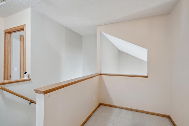 interior space featuring baseboards, light colored carpet, and a textured ceiling
