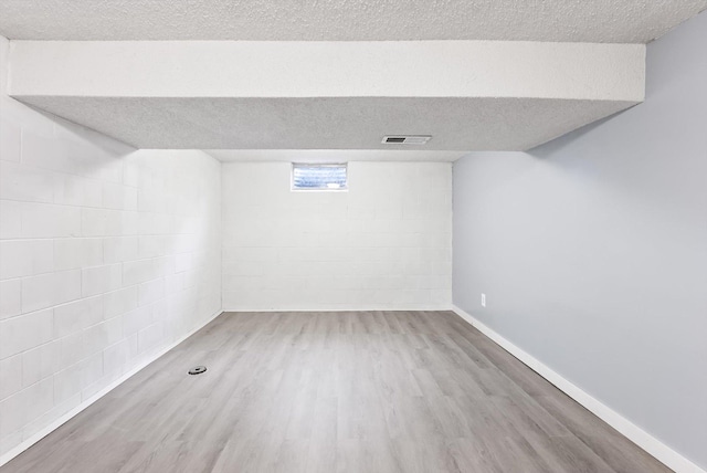 7986 Lad Pkwy, Brooklyn Park, MN 55443 - below grade area featuring wood finished floors, a textured ceiling, concrete block wall, and baseboards