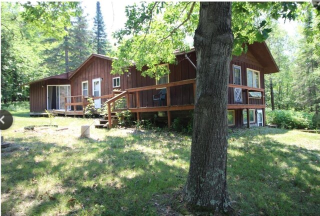 42491 432nd Ln, Aitkin, MN 56431 - rear view of property with board and batten siding, a lawn, a forest view, and a wooden deck