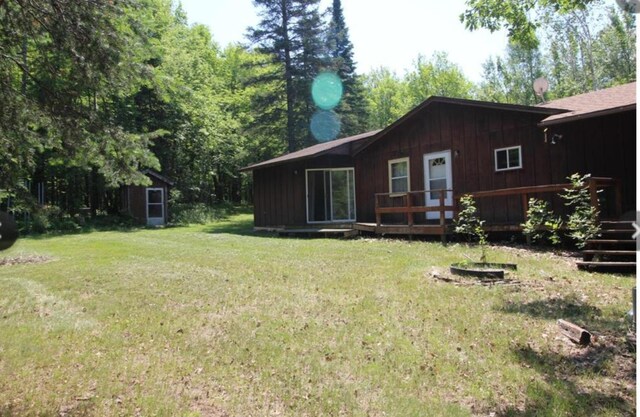 42491 432nd Ln, Aitkin, MN 56431 - rear view of property featuring a deck, a storage unit, board and batten siding, a lawn, and an outbuilding