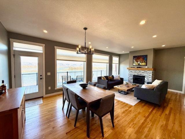 817 2nd St N, Brownsville, MN 55919 - dining space featuring a fireplace, baseboards, an inviting chandelier, and light wood-type flooring