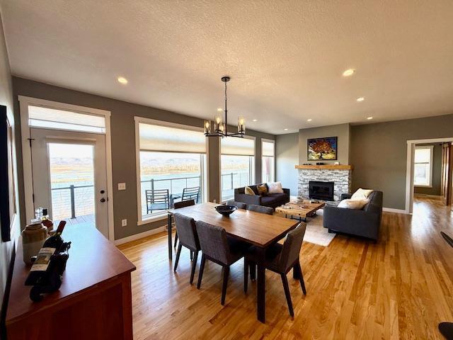 817 2nd St N, Brownsville, MN 55919 - dining area featuring light wood-style floors, baseboards, a fireplace, and a chandelier