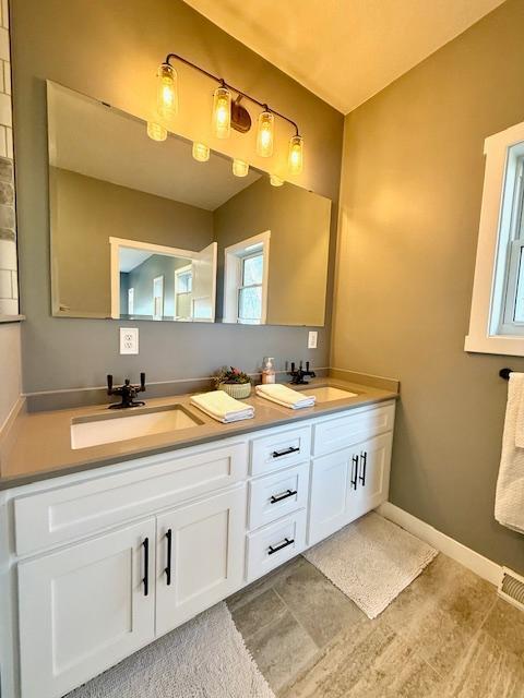 817 2nd St N, Brownsville, MN 55919 - full bathroom featuring double vanity, baseboards, and a sink