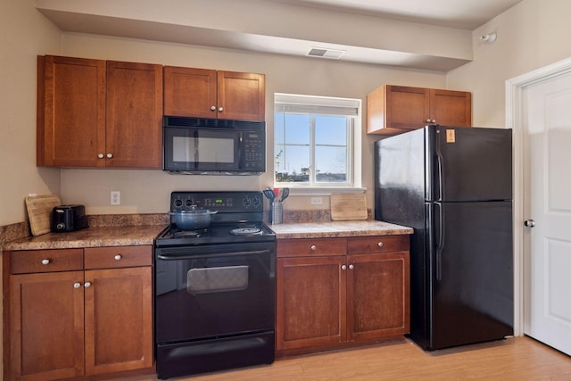 13560 Technology Dr Unit 1210, Eden Prairie, MN 55344 - kitchen featuring black appliances, light wood finished floors, and brown cabinets
