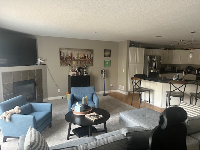 7048 Park Dr, Savage, MN 55378 - living area with a tiled fireplace, visible vents, baseboards, and a textured ceiling
