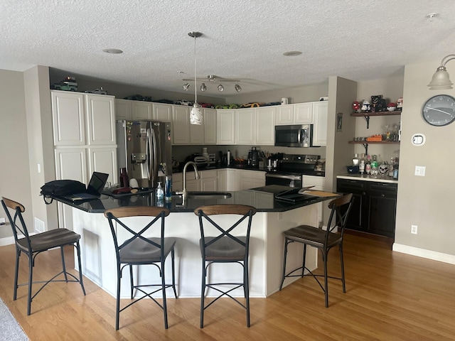 7048 Park Dr, Savage, MN 55378 - kitchen featuring white cabinets, light wood finished floors, a breakfast bar, appliances with stainless steel finishes, and a sink