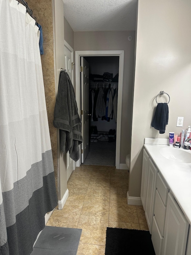 7048 Park Dr, Savage, MN 55378 - bathroom featuring vanity, a walk in closet, toilet, baseboards, and a textured ceiling