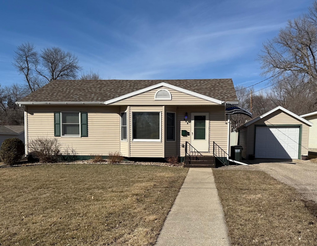 view of front of property featuring an outbuilding, roof with shingles, a detached garage, and a front yard