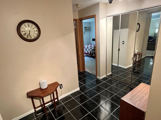 corridor with dark tile patterned floors, baseboards, and a wall mounted air conditioner
