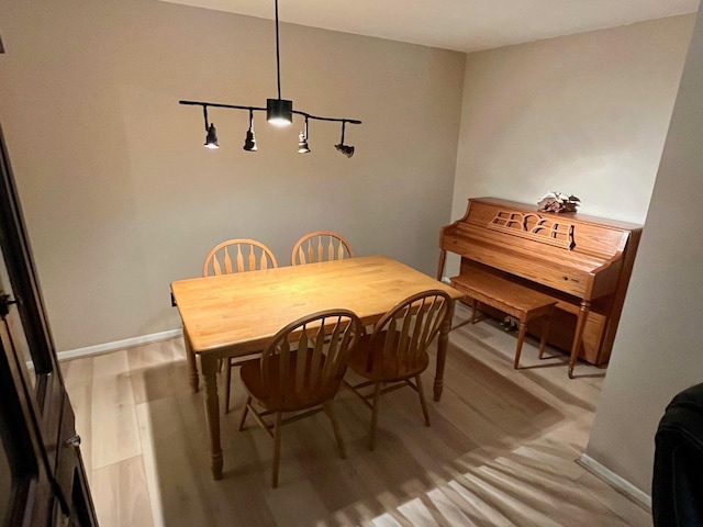 dining space featuring light wood-type flooring and baseboards