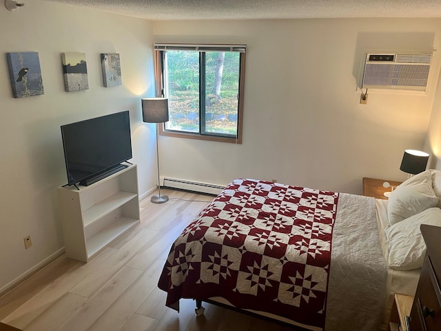 bedroom featuring a baseboard radiator, light wood finished floors, baseboards, a textured ceiling, and a wall unit AC
