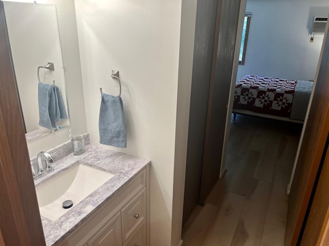 bathroom with wood finished floors, vanity, a wall mounted AC, and connected bathroom