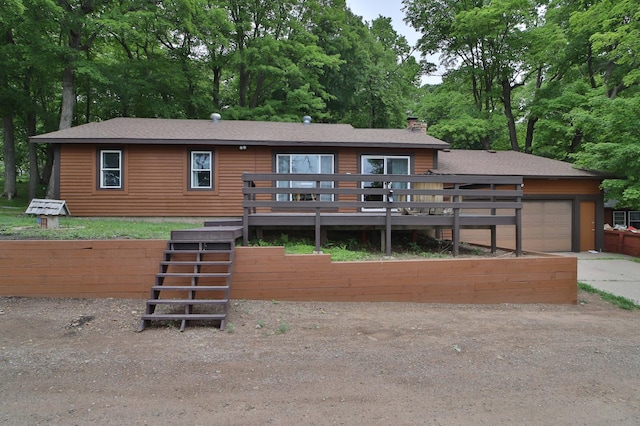 27672 Little Whitefish Rd, Garrison, MN 56450 - view of front facade with a chimney, concrete driveway, a deck, a garage, and a shingled roof