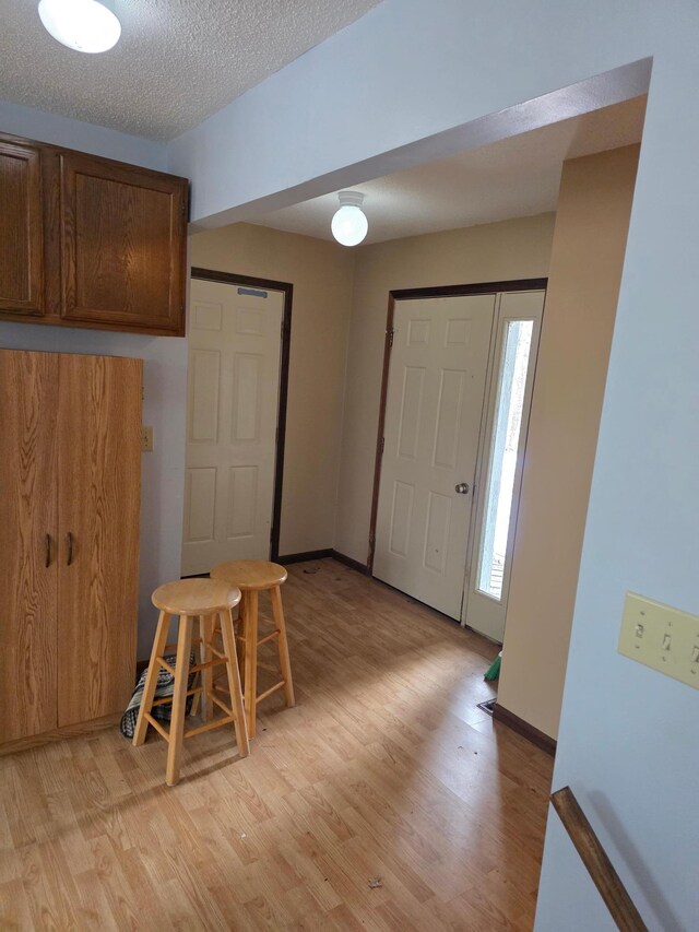 interior space with baseboards, light wood finished floors, and a textured ceiling