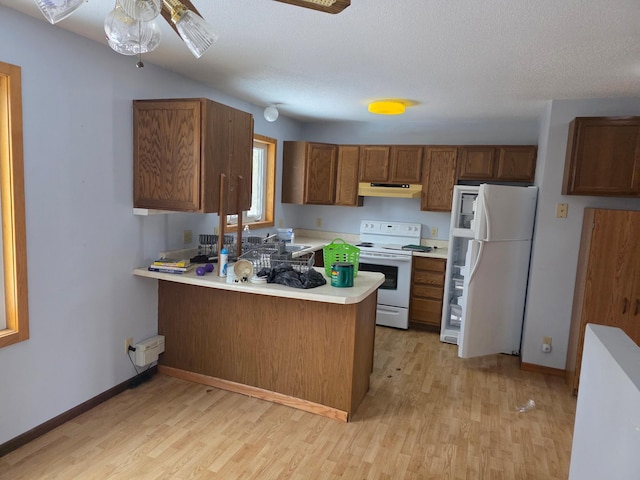 kitchen featuring white appliances, light wood-type flooring, light countertops, and a peninsula