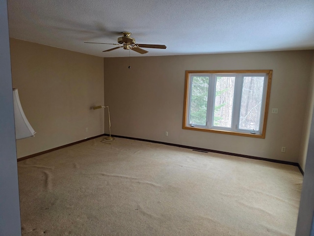 carpeted empty room featuring baseboards, visible vents, ceiling fan, and a textured ceiling