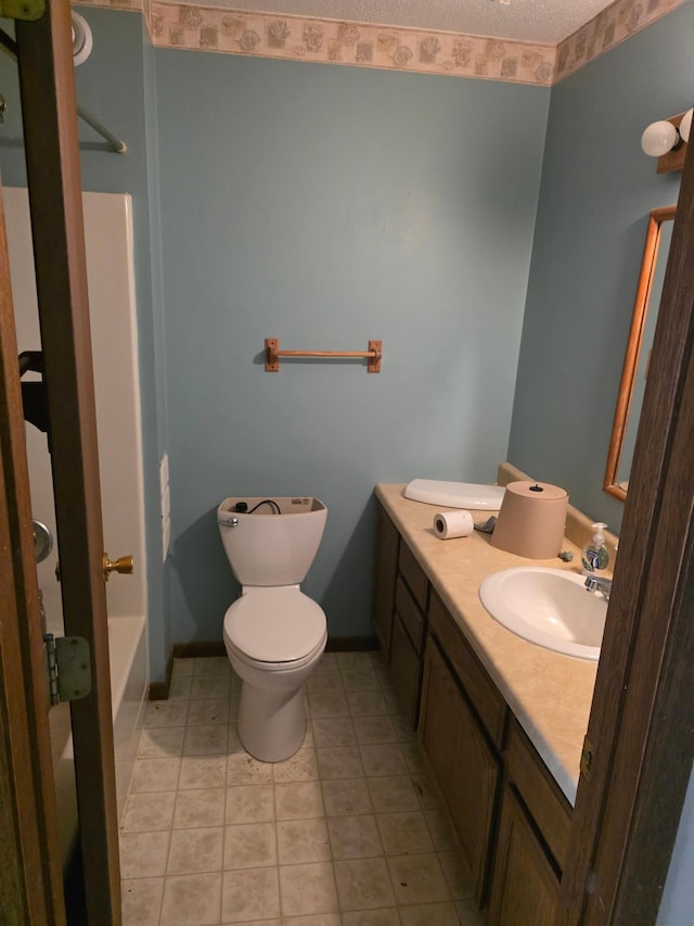 bathroom featuring tile patterned floors, toilet, vanity, a textured ceiling, and baseboards