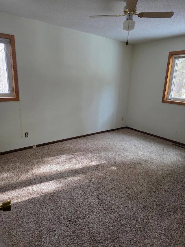 carpeted empty room featuring a textured ceiling, baseboards, and ceiling fan