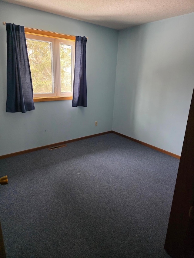 carpeted spare room with visible vents, baseboards, and a textured ceiling