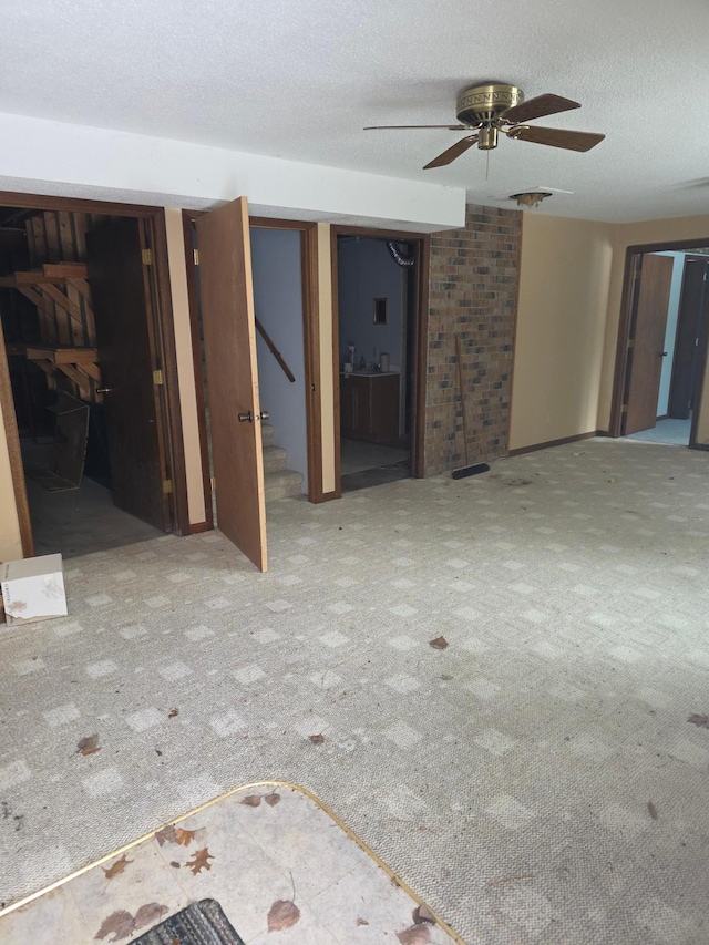 unfurnished living room with stairs, ceiling fan, carpet flooring, and a textured ceiling