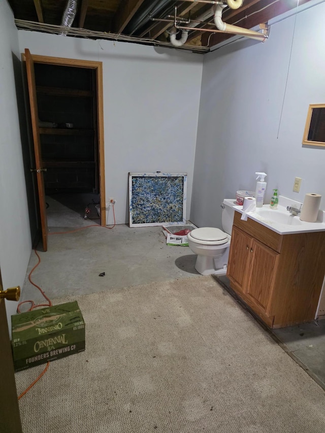 bathroom with unfinished concrete floors, toilet, and vanity