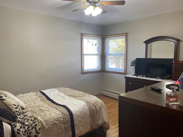 713 Maple Dr, Aurora, MN 55705 - bedroom with a baseboard heating unit, a ceiling fan, and light wood-style floors
