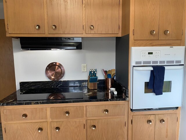 713 Maple Dr, Aurora, MN 55705 - kitchen with light brown cabinetry, under cabinet range hood, dark countertops, black electric stovetop, and white oven