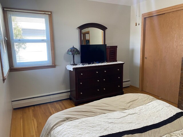 713 Maple Dr, Aurora, MN 55705 - bedroom featuring a baseboard radiator, wood finished floors, multiple windows, and a closet