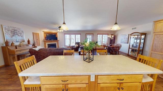 kitchen featuring visible vents, a fireplace, ceiling fan, dark wood-style floors, and light countertops
