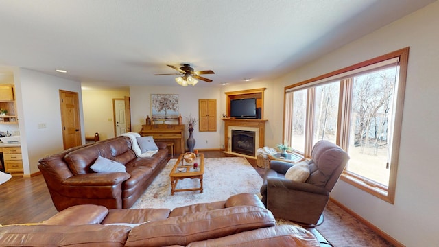 living room featuring baseboards, ceiling fan, and a healthy amount of sunlight