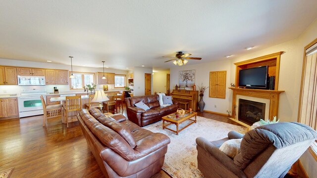 living area featuring a glass covered fireplace, recessed lighting, ceiling fan, and hardwood / wood-style flooring