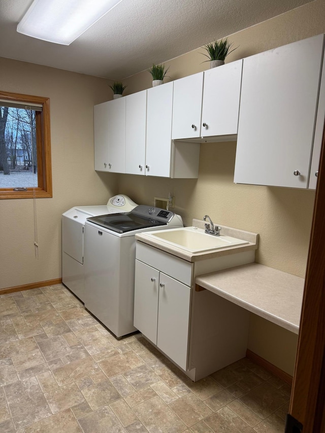 laundry area featuring separate washer and dryer, baseboards, stone finish floor, and cabinet space