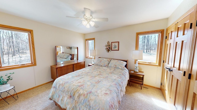 bedroom featuring baseboards, multiple windows, light carpet, and ceiling fan