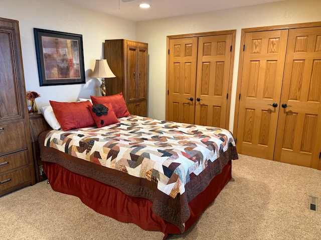 carpeted bedroom with recessed lighting and two closets