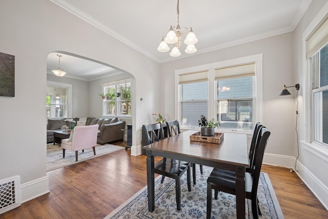 4336 Aldrich Ave S, Minneapolis, MN 55409 - dining space with arched walkways, wood finished floors, a chandelier, ornamental molding, and baseboards