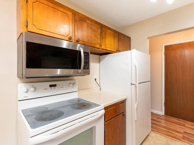 4351 Parklawn Ave Unit 209E, Edina, MN 55435 - kitchen featuring white appliances, brown cabinetry, light countertops, and light tile patterned floors