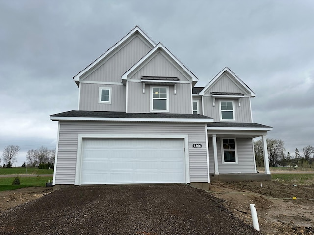 view of front of house featuring board and batten siding, an attached garage, covered porch, and aphalt driveway