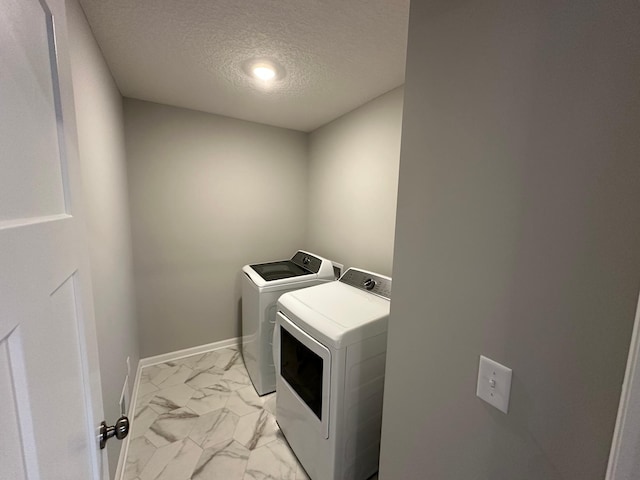 clothes washing area featuring a textured ceiling, marble finish floor, baseboards, washer and dryer, and laundry area