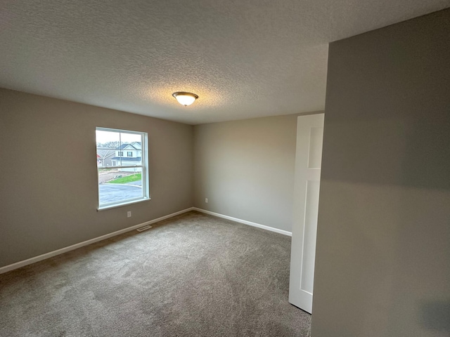 empty room featuring a textured ceiling, visible vents, carpet floors, and baseboards