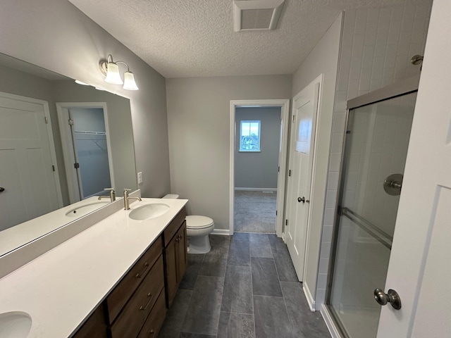 bathroom featuring a textured ceiling, visible vents, a shower stall, and vanity